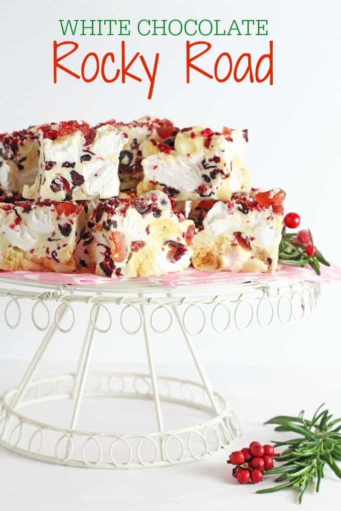 Slices of White Chocolate Rocky Road stacked on a white wire cake stand.