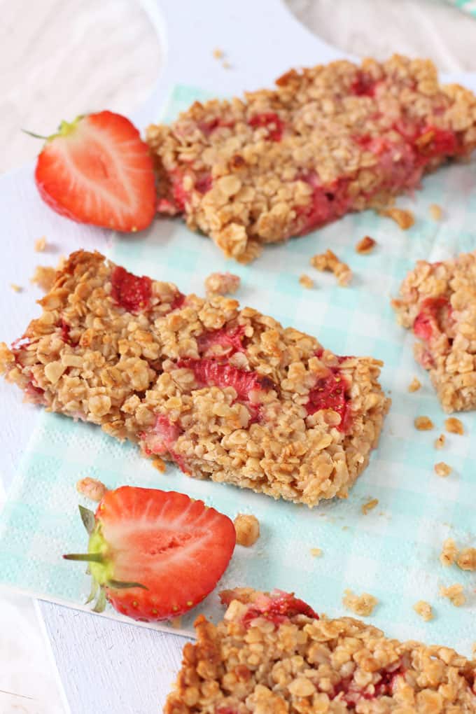 Strawberry Oat Bars on a blue and white gingham napkin garnished with sliced strawberries.