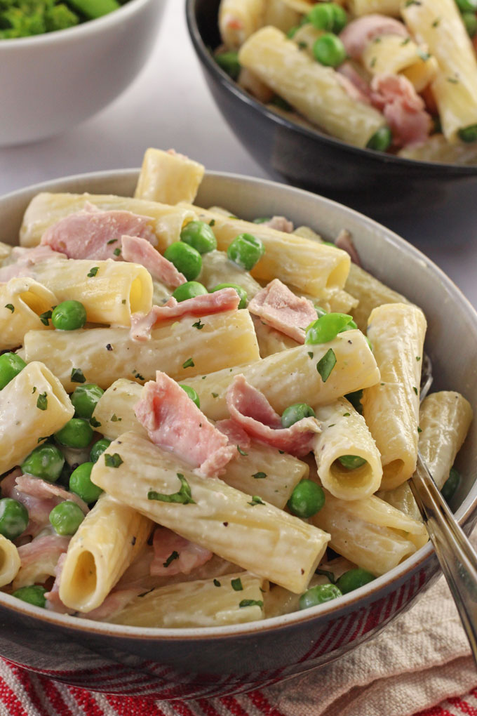 A close up shot of the Creamy Ham & Pea Pasta in a bowl with a fork in it.