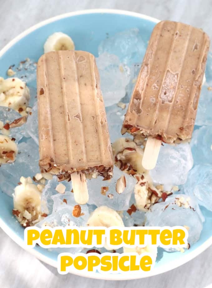 Tow peanut butter and banana popsicles laying on a bed of ice in a blue and white bowl.