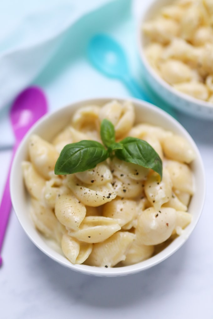 One pot cheesy cauliflower pasta served in a small white bowl and garnished with basil leaves.
