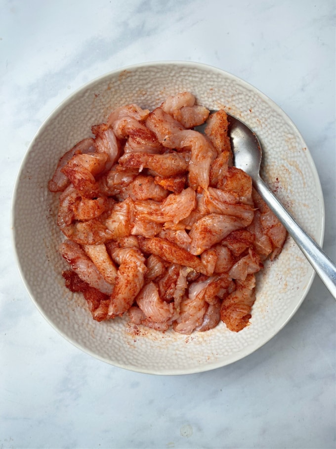 strips of turkey steak in a bowl mixed with paprika, garlic and onion powder