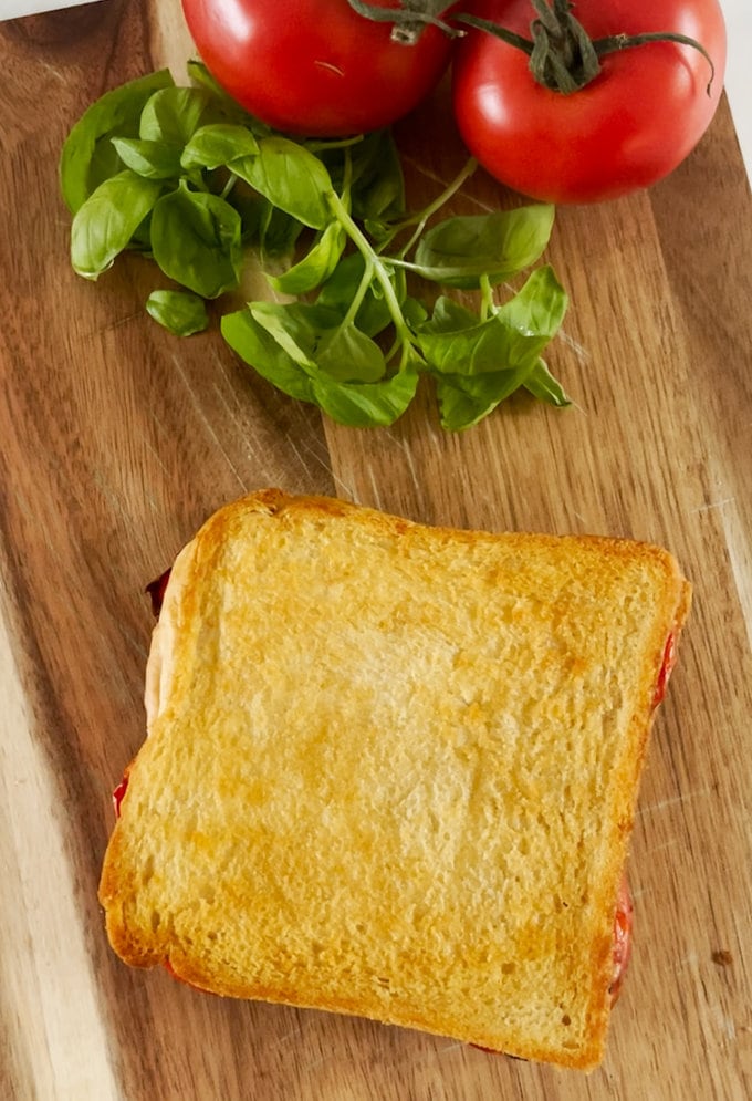 Cooked and golden brown toastie presented on a wooden chopping board.