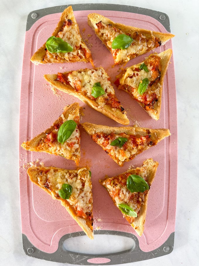 Air fryer pizza toast, cut into triangle shaped pieces and some fresh basil leaves added for some extra flavors.