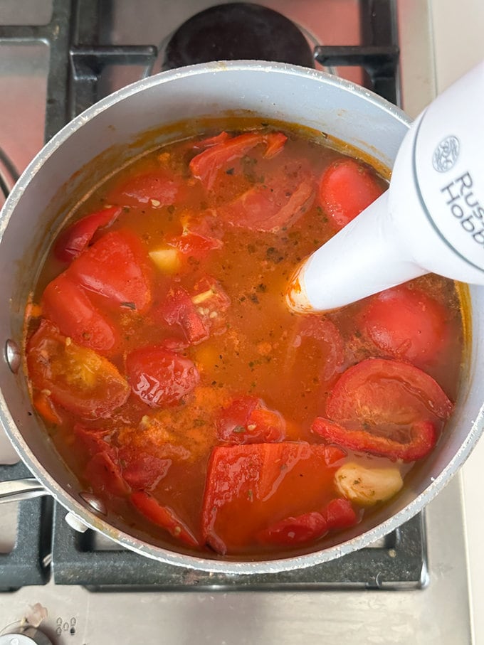 Ingredients being blitzed with a food blender in the saucepan.