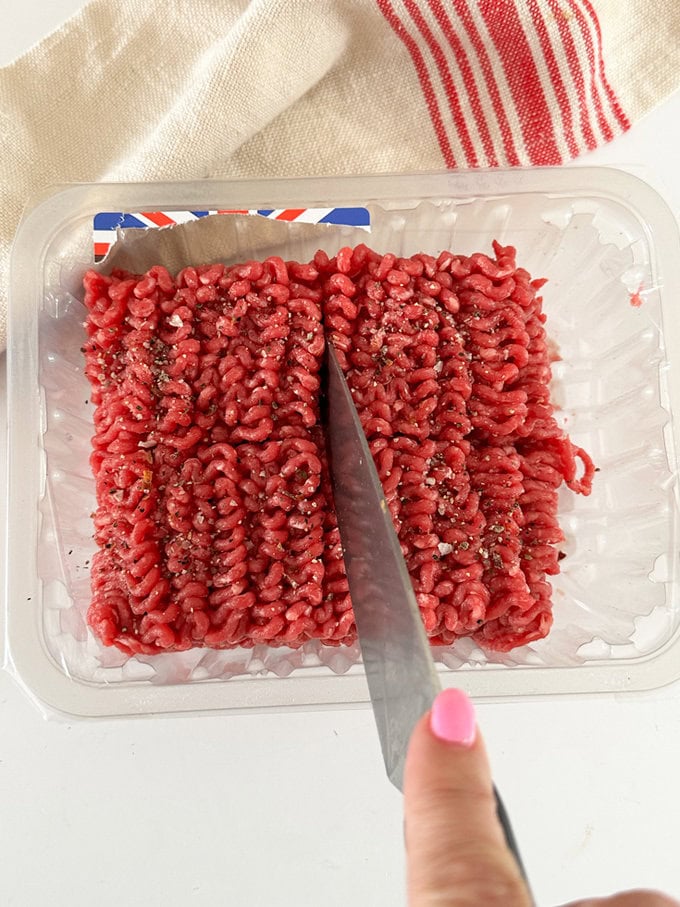 Mince beef being cut into four equal sections with a sharp knife.