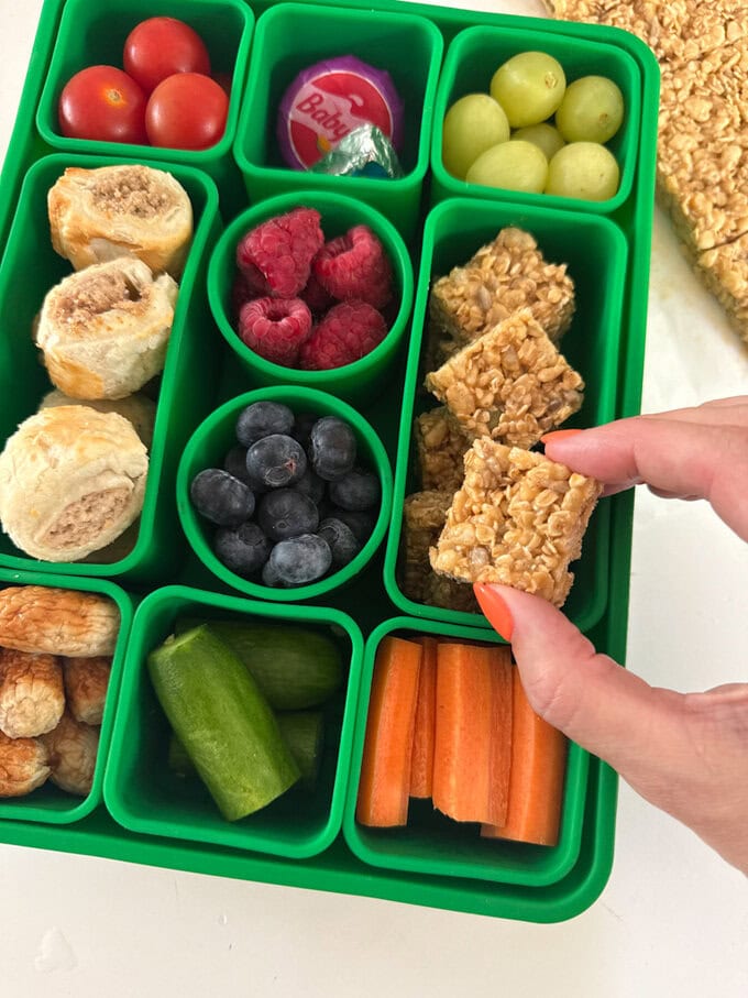 Mini No Bake Granola Bites served in a bright green kids snackle box along with lots of other tasty snacks.