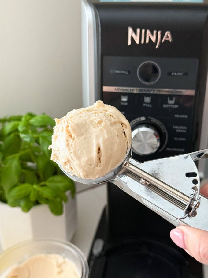 Frozen yogurt made in the Ninja Creami with peanut butter and banana being served using a stainless steel ice cream scoop.